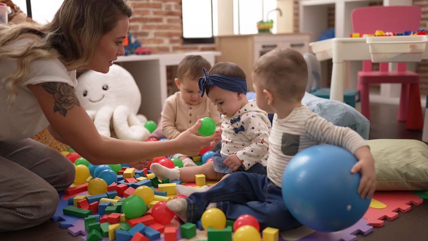 A teacher and children playing on the classroom floor