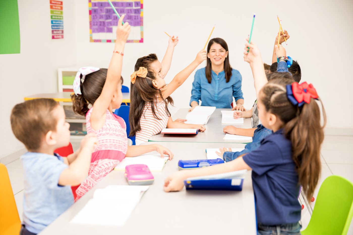 School-age children raising their hands in class
