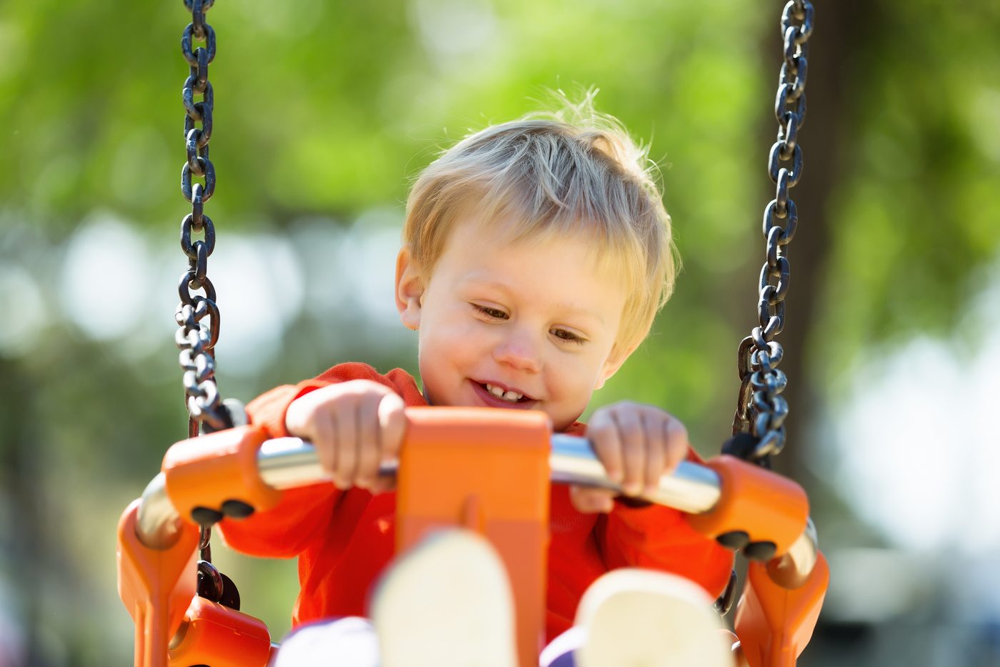A baby laughing in a swing outdoors
