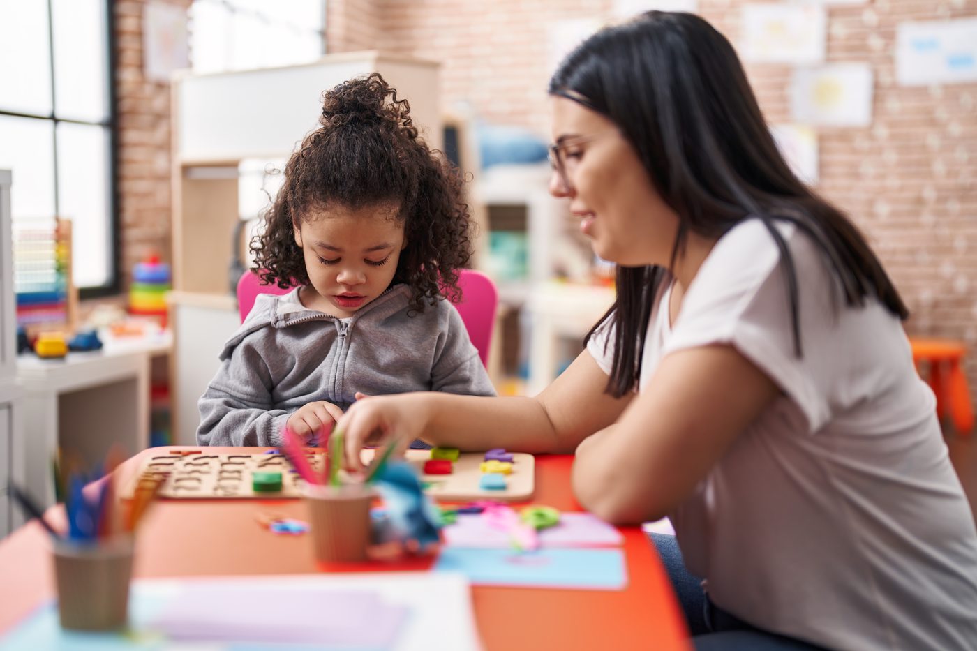 A teacher and a toddler working a number puzzle
